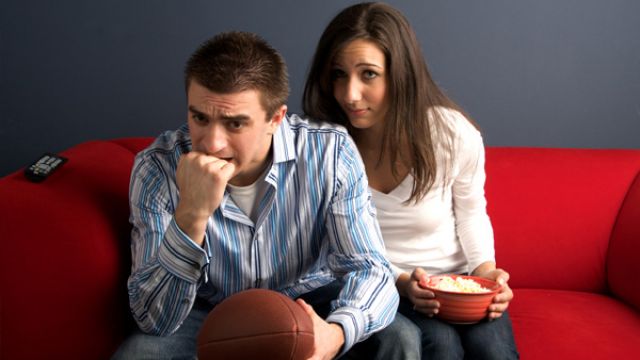 bored-woman-watching-football-with-husband.jpg